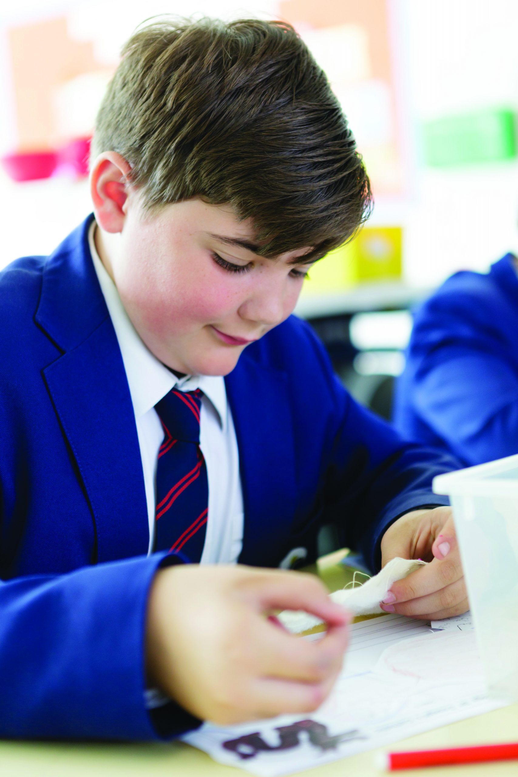 A boy in school uniform working at a desk