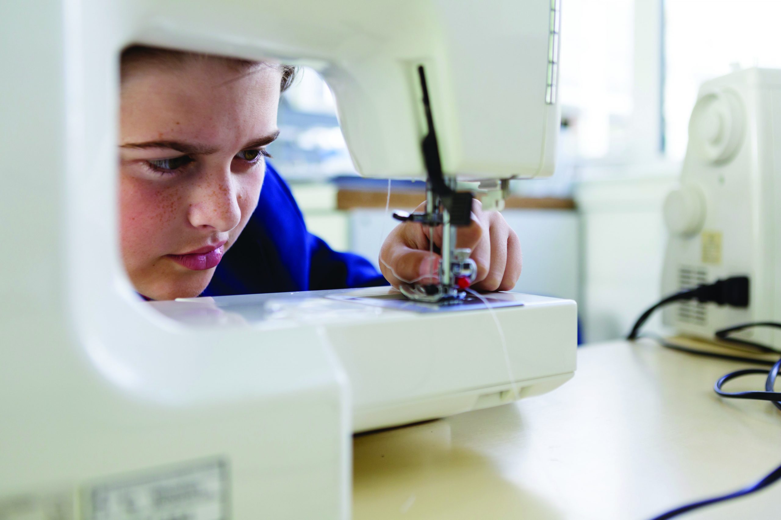 A boy using a sewing machine