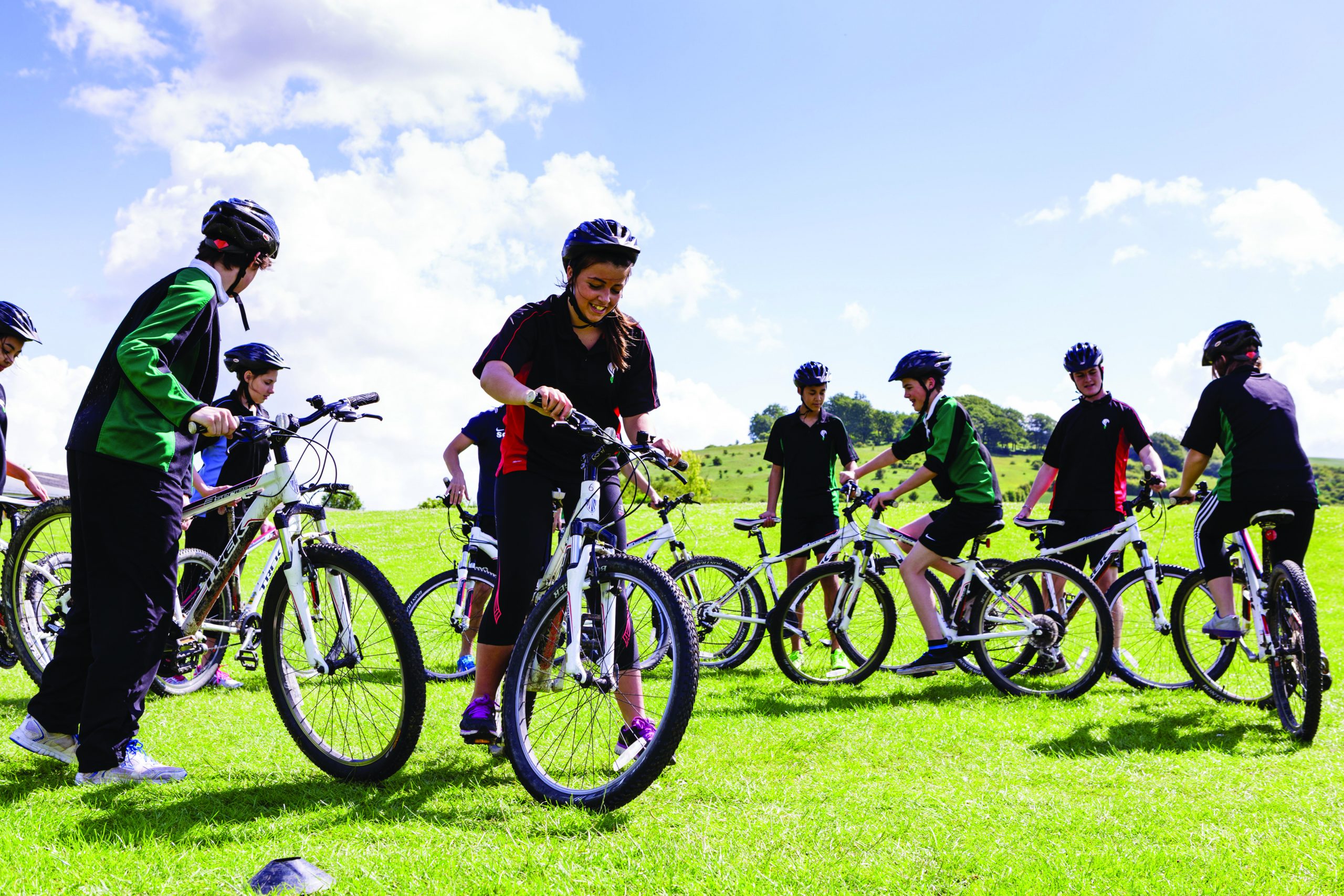 A group of pupils riding bikes on the school field in PE kit