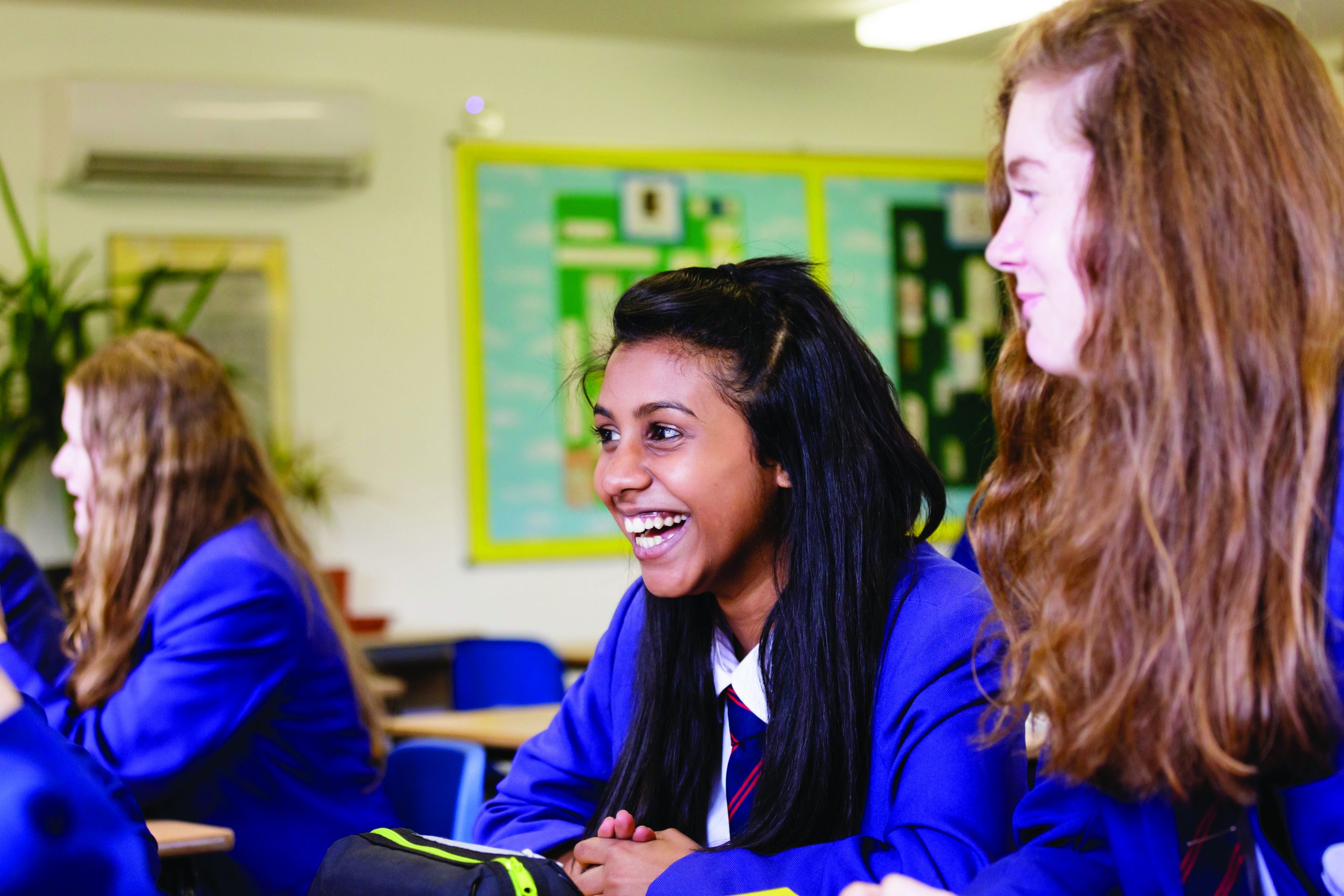 A group of girls sitting at a table. One of them is laughing