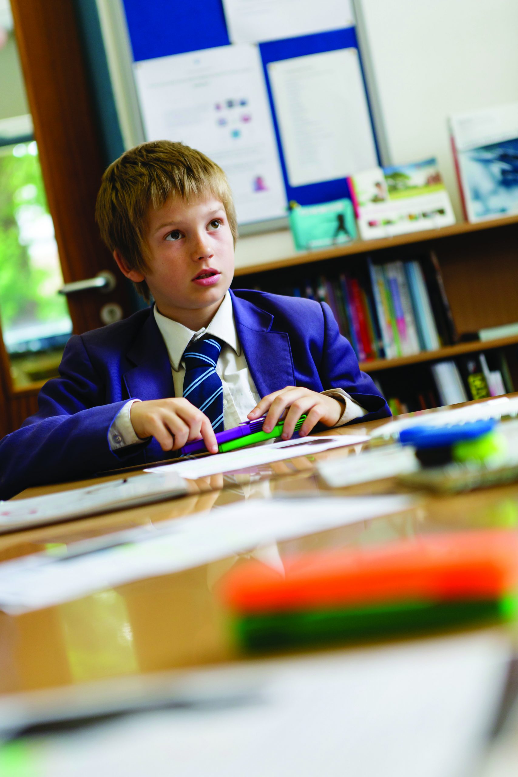 A boy sitting at a desk with stationery on the table