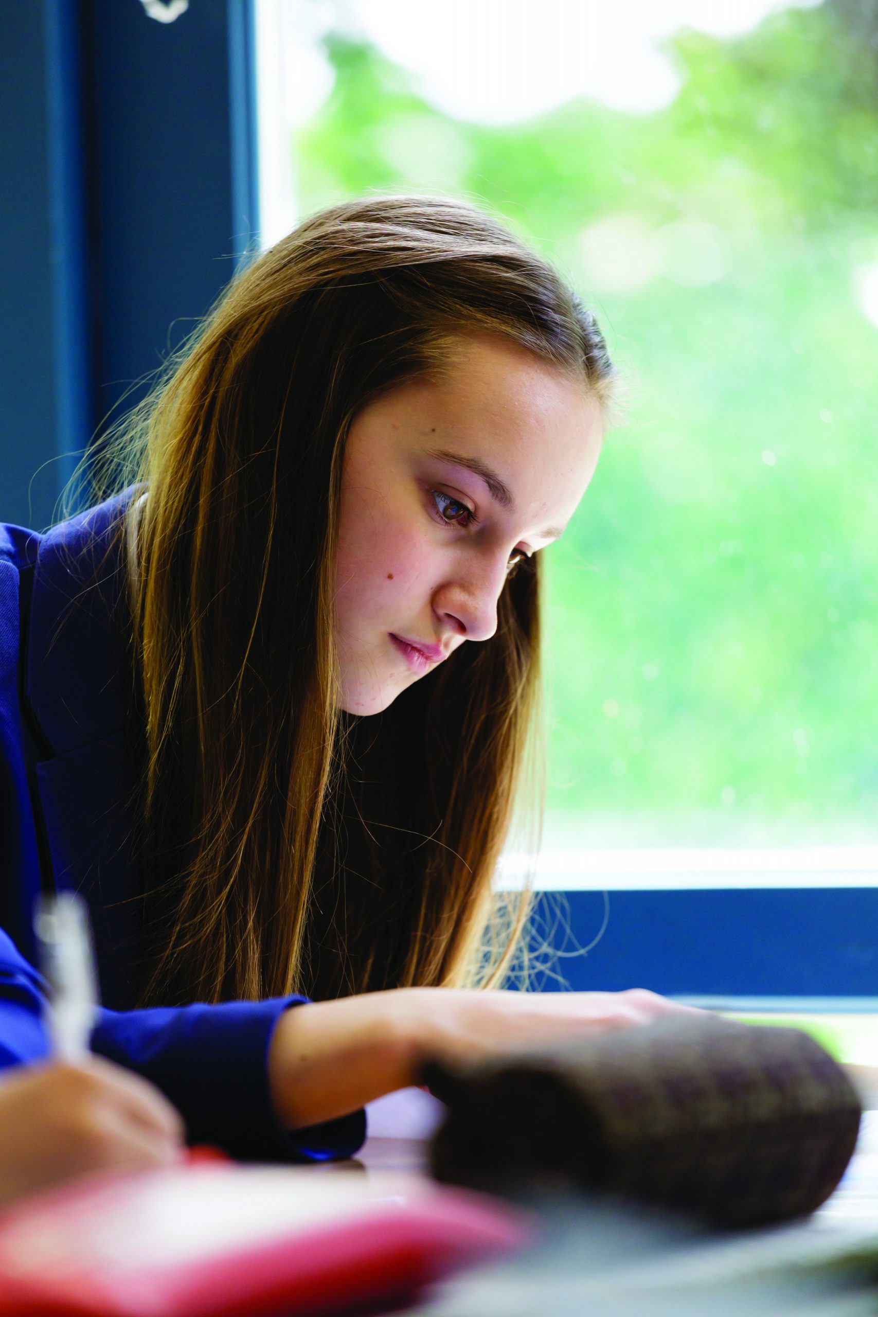 A girl sitting at a desk by a window