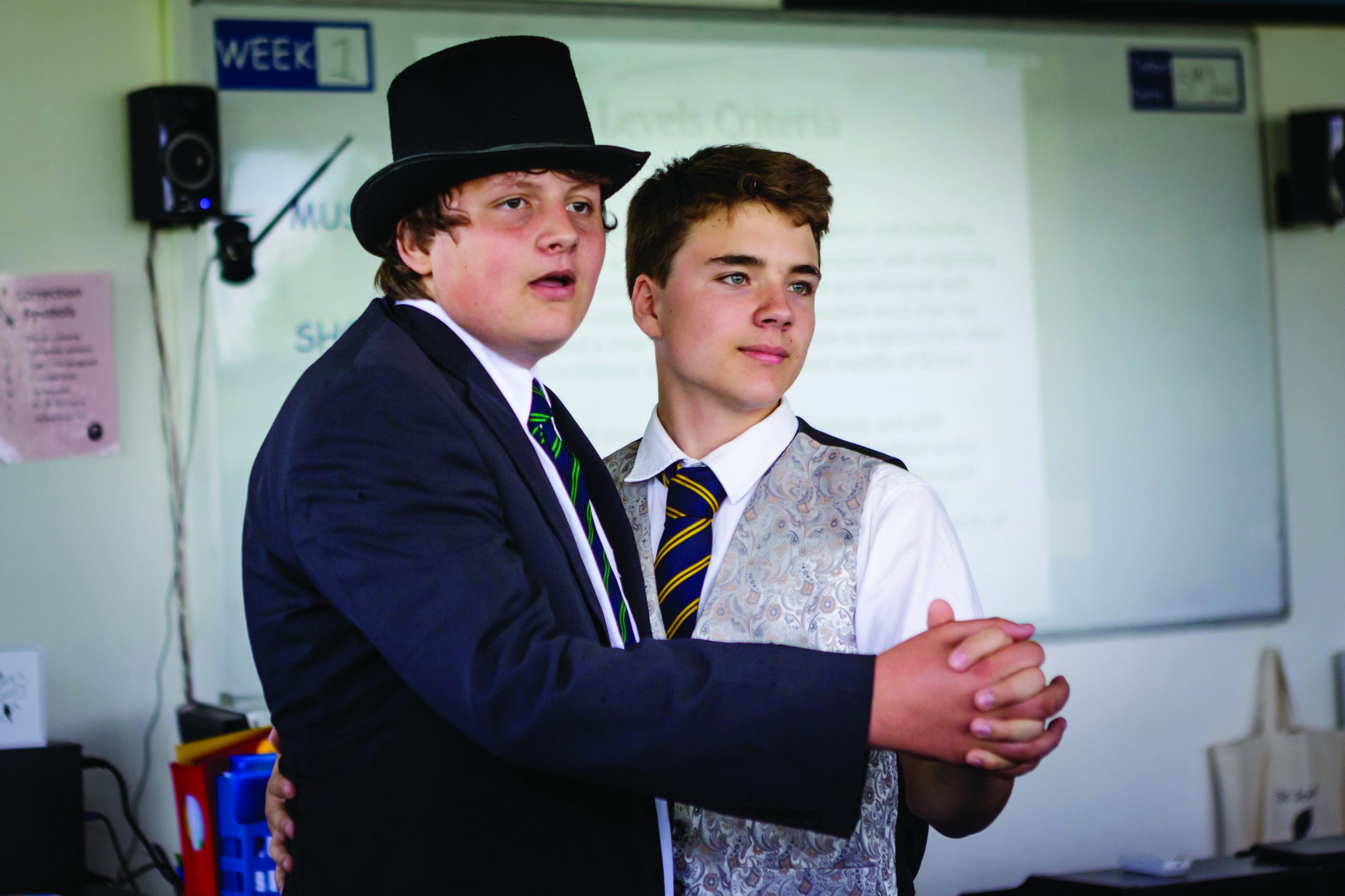 Two boys, one wearing a top hat, rehearsing in the drama room