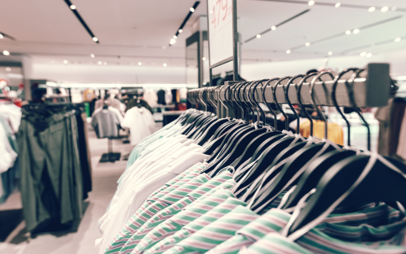 Clothes hanging up on a rail in a retail shop