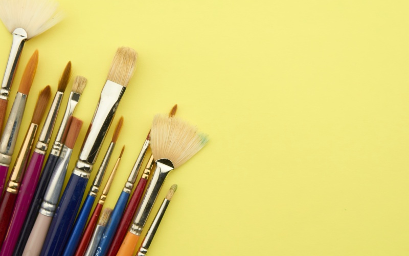 Paintbrushes on a plain yellow background