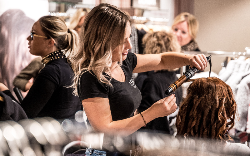 A hairdresser curling a woman's hair in a salon
