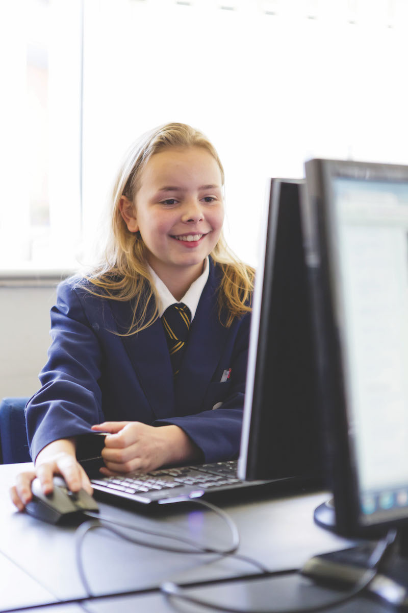 A girl in school uniform using a computer