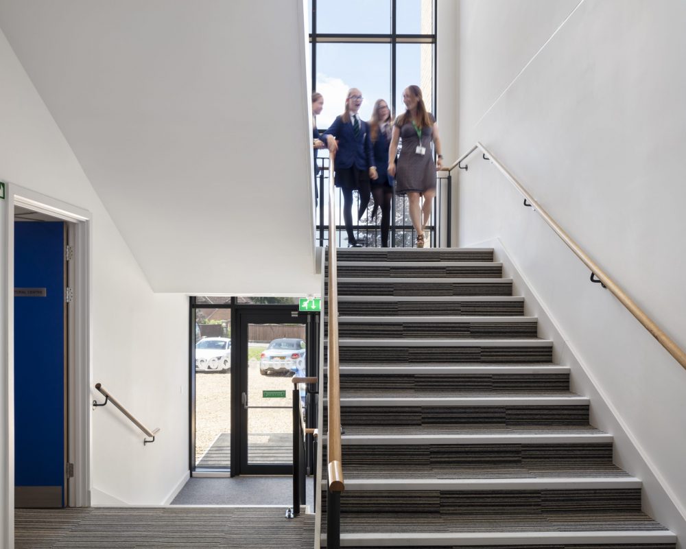 A group of pupils and a teacher walking downstairs