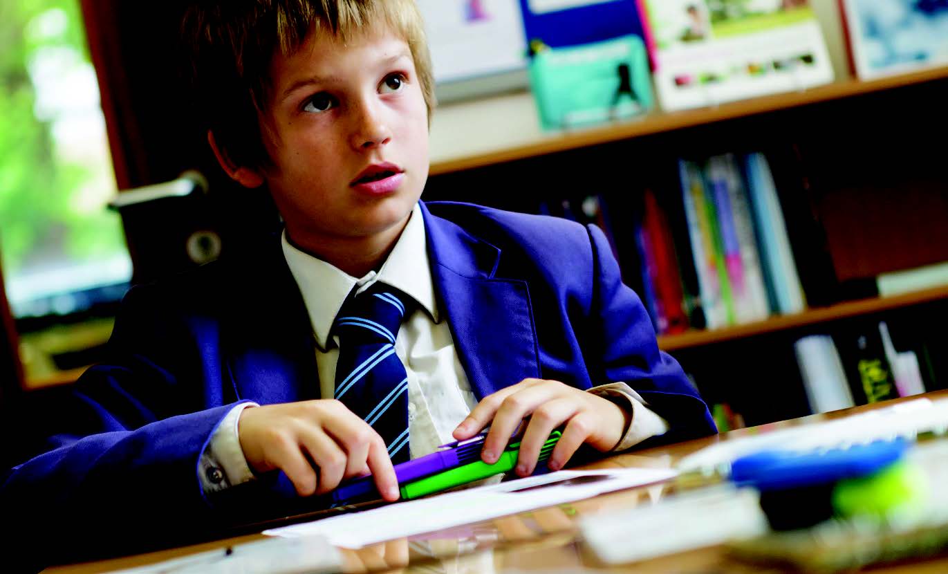 A boy in school uniform working at a desk