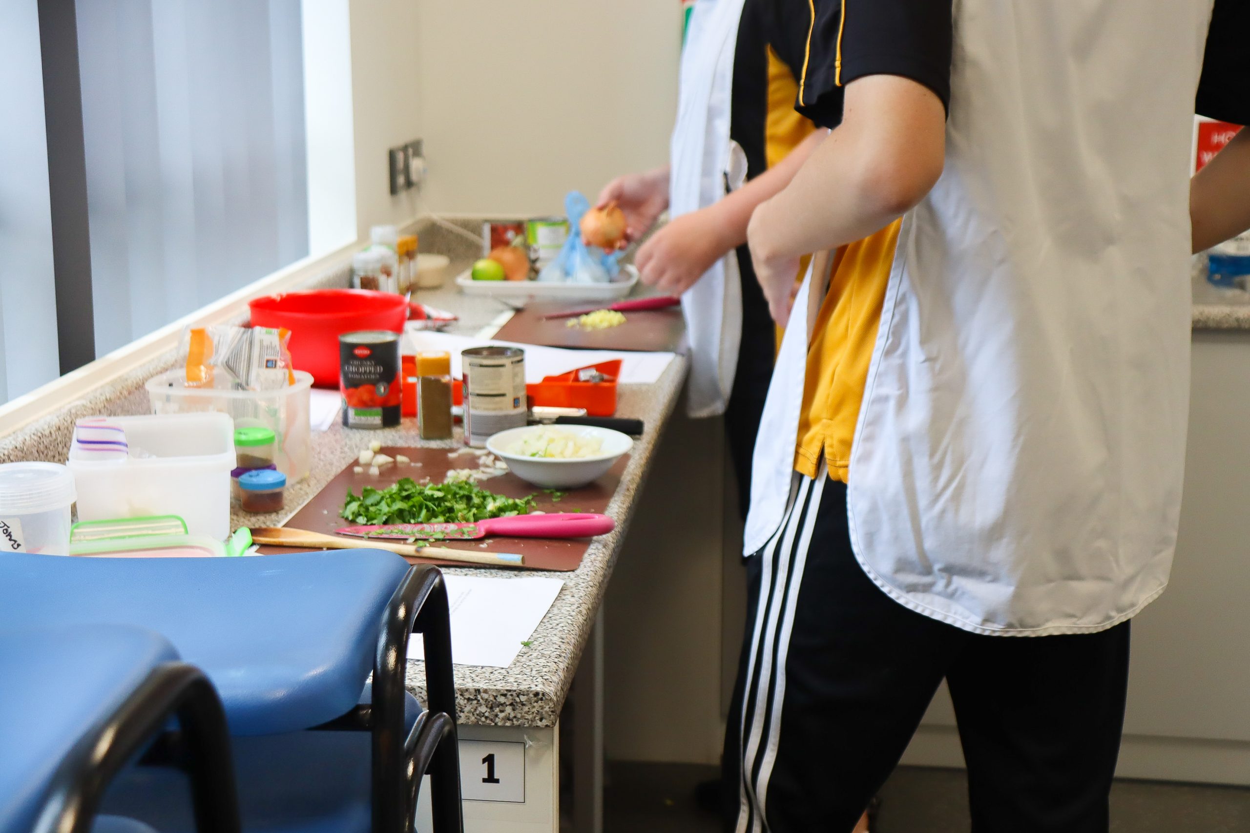 Pupils cooking. The workshop is covered in chopping boards, tins, bowls and ingredients